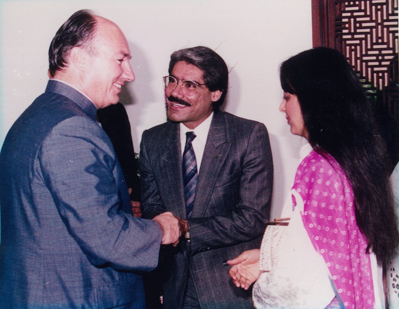 His Highness the Aga Khan shaking hands with Dr. Abdulla, smiling, as Almas looks on, 1988