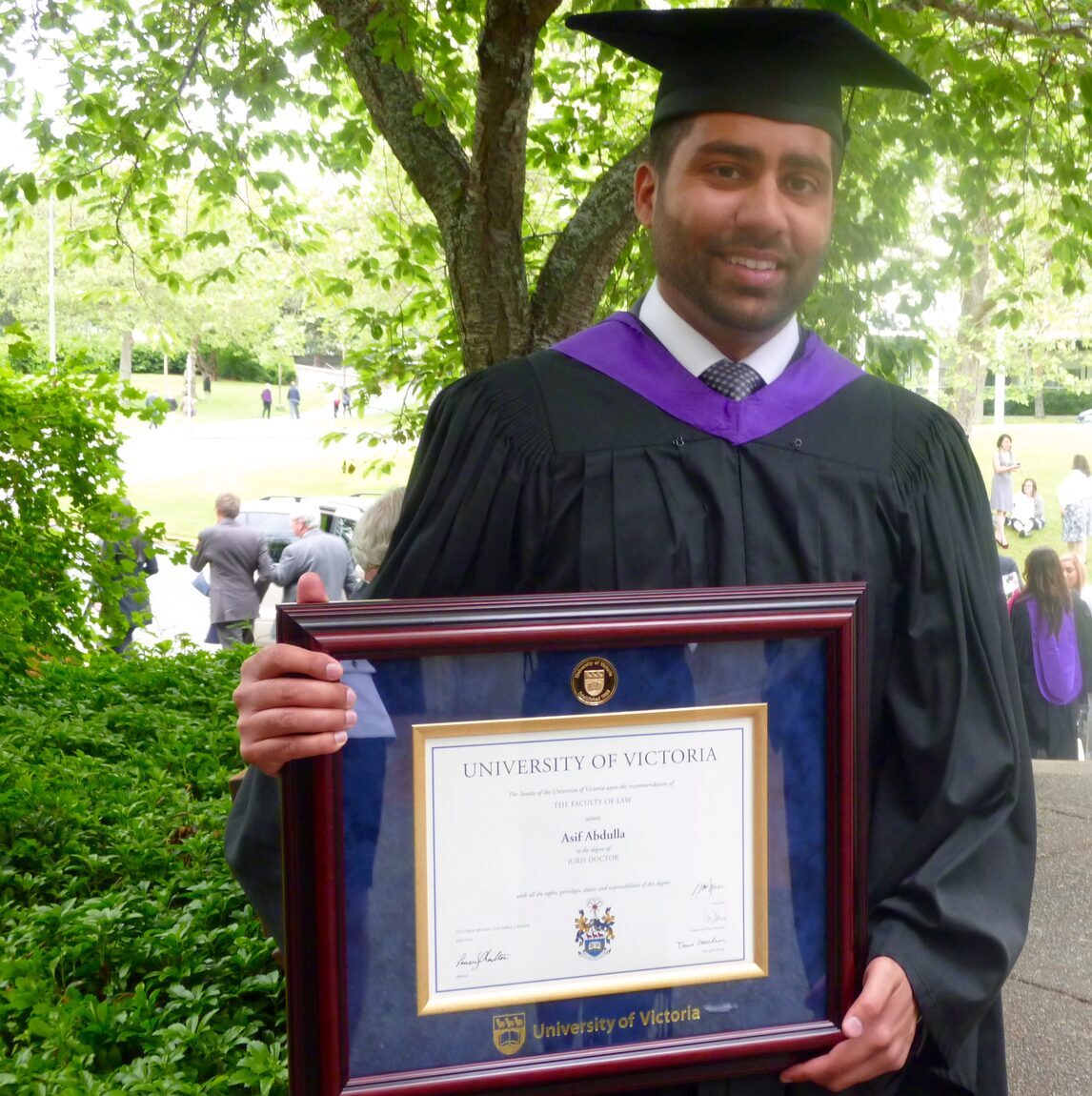 Asif Abdulla holding his framed Juris Doctor diploma from the University of Victoria